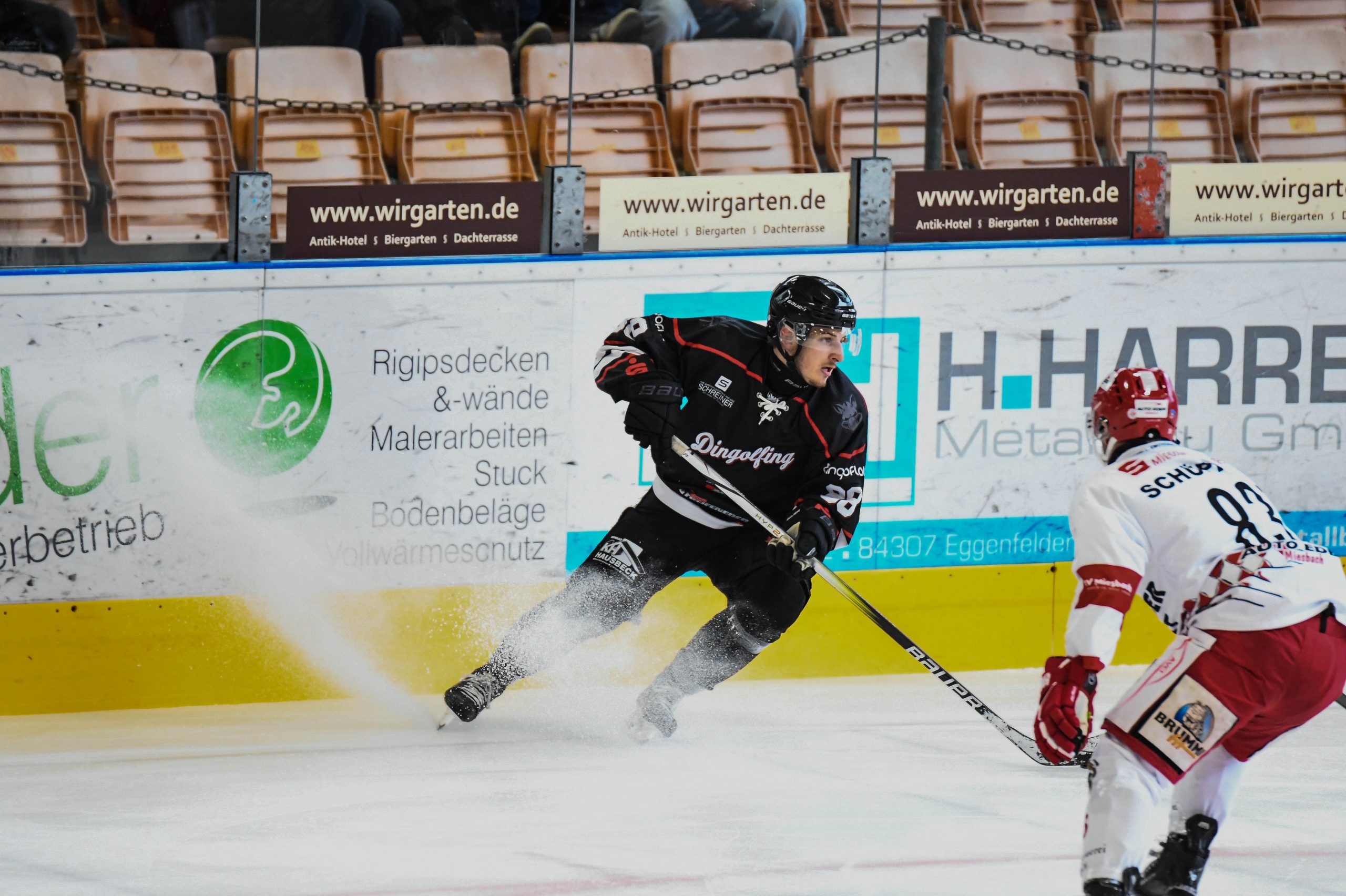 Joey Oberrauch (EV Dingolfing)am Puck vor Reto Schüpping Schuepping (TEV Miesbach), Eishockey Herren, Bayernliga, 3.Spieltag, Saison 2025 2026 am 19.10.2025 in der Marco Sturm Eishalle in Dingolfing, EV Dingolfing (schwarz) gegen TEV Miesbach (weiss) Foto: Hockeypics/ Eva Fuchs